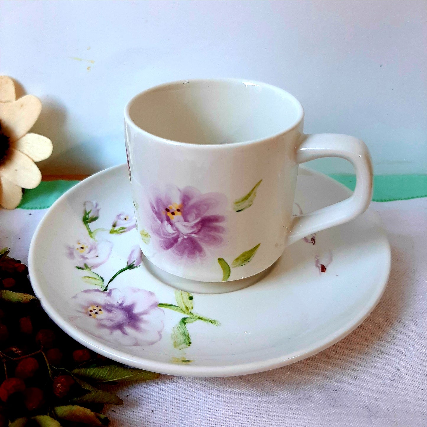 Hand-painted small coffee set, featuring a small bouquet of mauve roses on the exterior and another bouquet inside the cup."